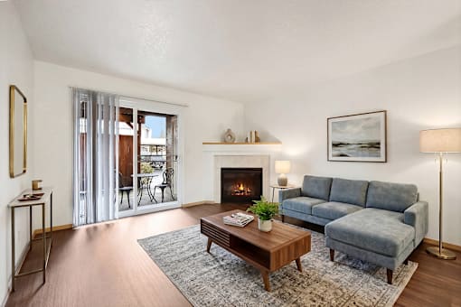 A living room with a grey couch, a coffee table, a fireplace, and a painting on the wall.