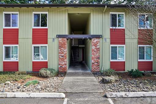 A building with a red and green exterior and a covered walkway leading to the entrance.