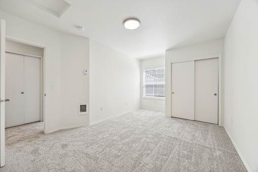 A spacious room with carpeted floor and white walls.