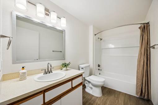 A bathroom with a white toilet, sink, and a mirror above the sink.