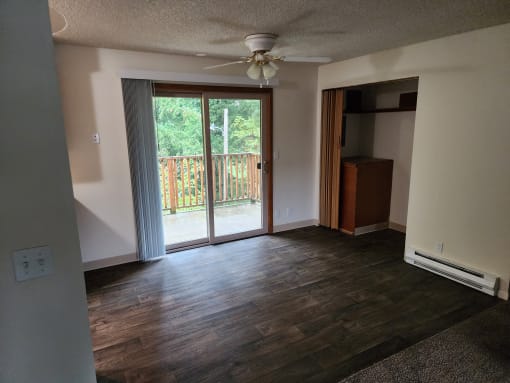an empty living room with a sliding glass door to a balcony