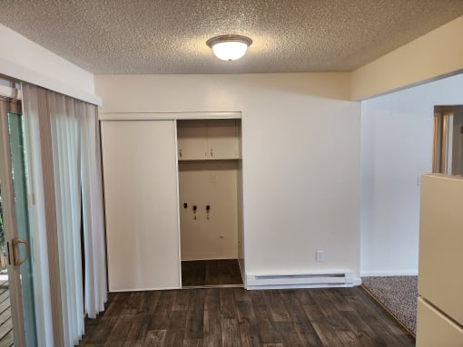 an empty living room with a hallway to a closet and a door to a room