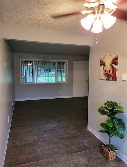 A room with a ceiling fan and a painting of a cow on the wall.