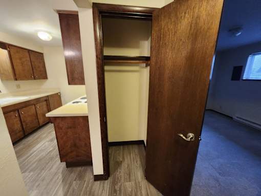 A brown door is open to a small kitchen.