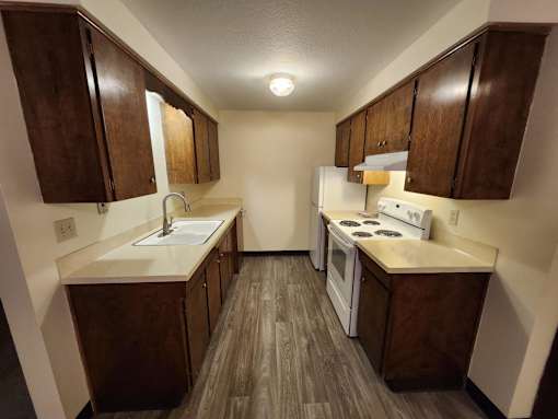 A kitchen with white appliances and wooden cabinets.