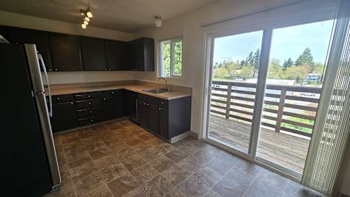 A kitchen with black cabinets and a tiled floor.