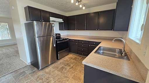 A kitchen with a stainless steel refrigerator and black cabinets.