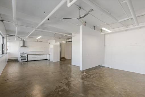 A large empty room with white walls and a concrete floor.