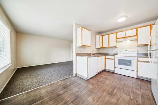 A kitchen with white cabinets and a wooden floor.