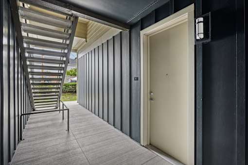 A long corridor with a staircase on the left and a door on the right.