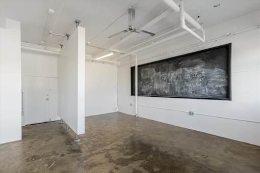 A room with a chalkboard on the wall and a white door.
