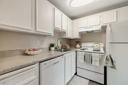 A white kitchen with a refrigerator, oven, and sink.