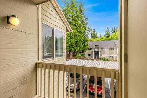 A balcony with a red car parked in the driveway.