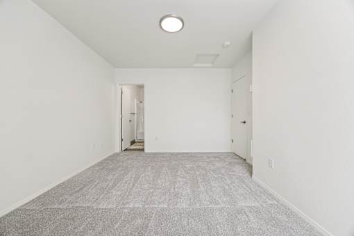 A large, empty room with a carpeted floor and white walls.