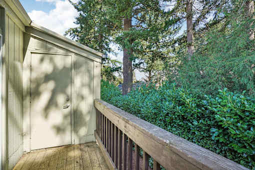 A wooden deck with a white door and a wooden railing.