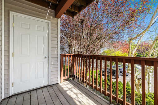 A white door is on the left of a wooden deck.