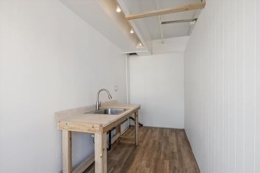A kitchen with a sink and wooden table.