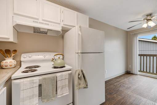 A kitchen with a white stove and a white refrigerator with a white wall and a white ceiling.