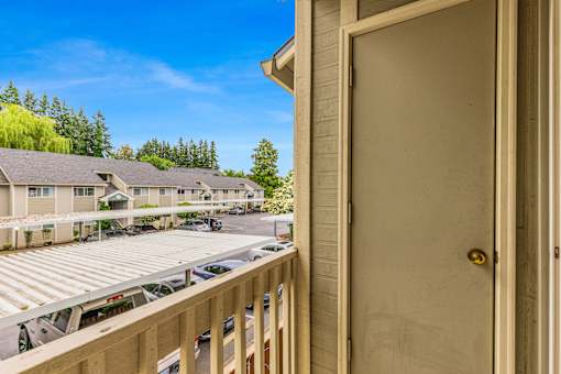 A view from a balcony of a building with a car parked in the driveway.