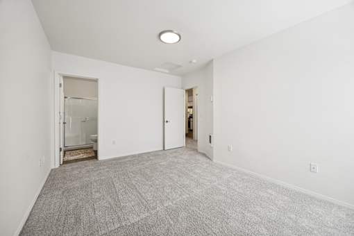 A large, empty room with a carpeted floor and a single light fixture on the ceiling.