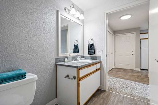 A white bathroom with a white toilet, sink, and mirror.