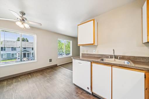 A kitchen with white cabinets and a window overlooking a house.