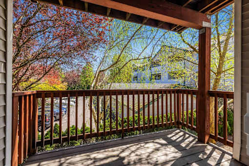 A wooden deck with a railing and trees in the background.
