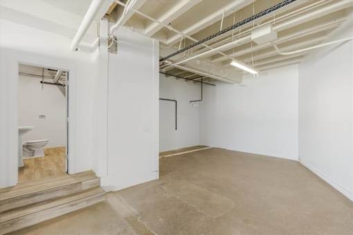 A room with a toilet and a door leading to another room.