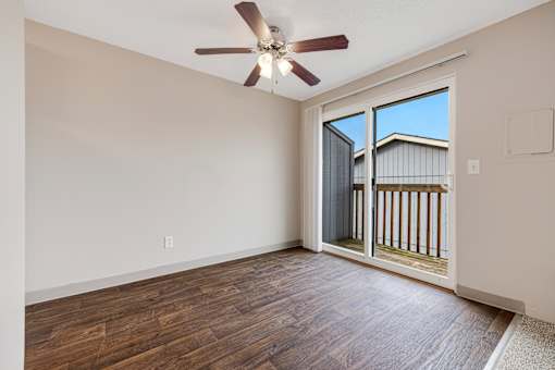 A room with a ceiling fan and sliding glass doors.
