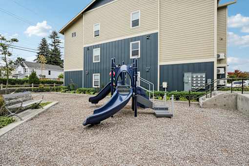 A playground with a blue slide in front of a building.