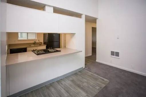 A kitchen with a black refrigerator and a wooden floor.