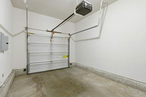 A garage door is closed and there is a white wall behind it.