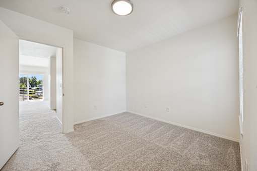 A large, empty room with a carpeted floor and white walls.