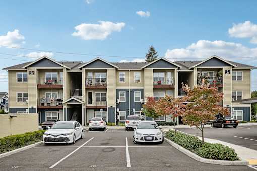 A row of townhouses with cars parked in front.