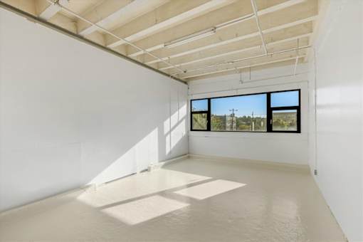 A large empty room with a window overlooking a street.