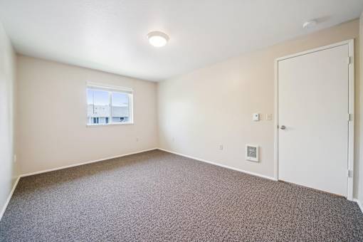 A room with a carpeted floor and a window.