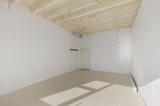 A white room with a door and a ceiling with pipes.