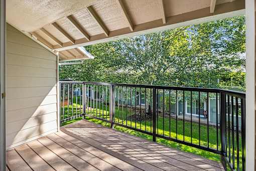 A balcony with a black railing and a wooden floor.