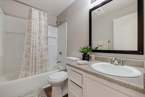 A white bathroom with a sink, toilet, and shower.