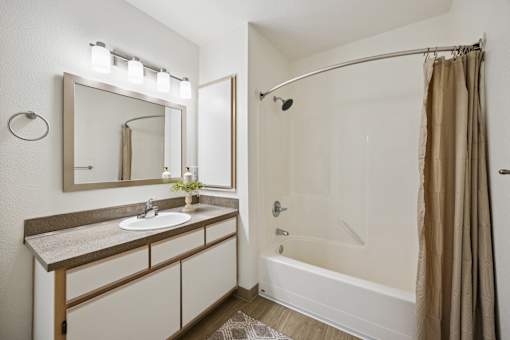A bathroom with a sink, mirror, and bathtub.
