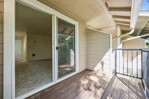 A sunny day with a balcony and sliding glass door.