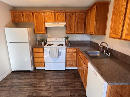 A kitchen with wooden cabinets and a white fridge.