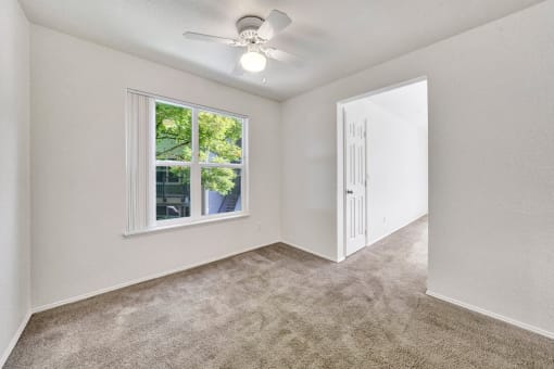 an empty bedroom with a ceiling fan and a window