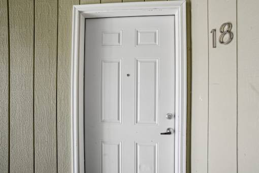 A white door with a black handle is set in a white frame.