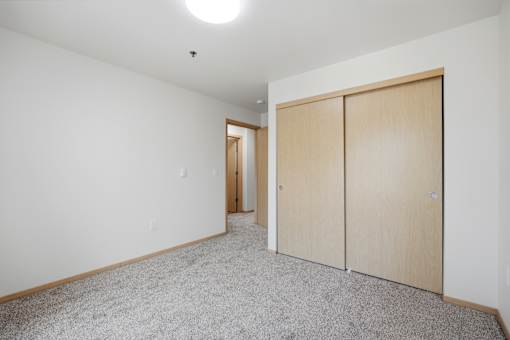 A room with a carpeted floor and two wooden doors.