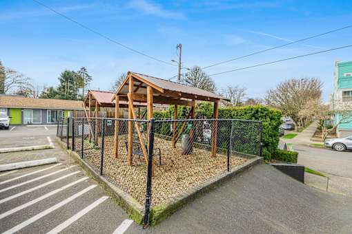 A playground with a wooden structure and a black fence.