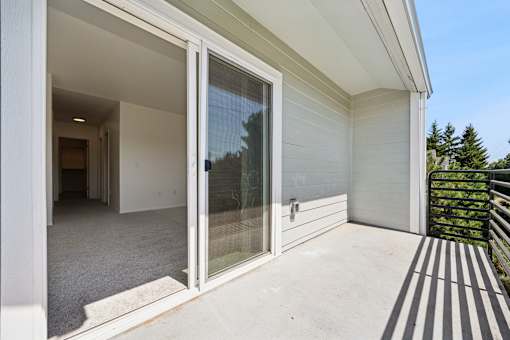 A patio with a sliding glass door and a striped rug.