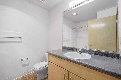 A bathroom with a toilet, sink, and mirror.