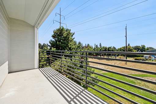 A balcony with a metal railing overlooks a field.
