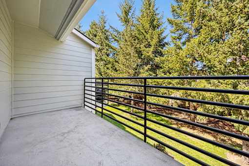 A balcony with a black railing overlooking a green tree.